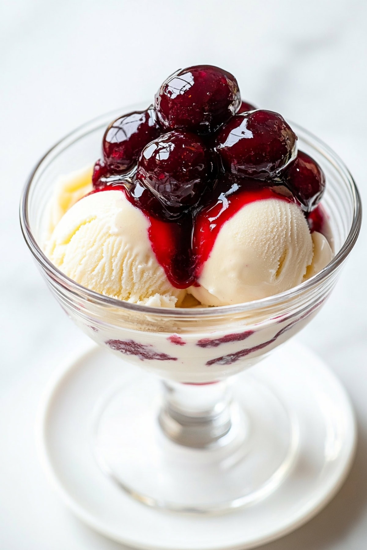 A serving glass of vanilla ice cream and warm, sticky Cherries Jubilee