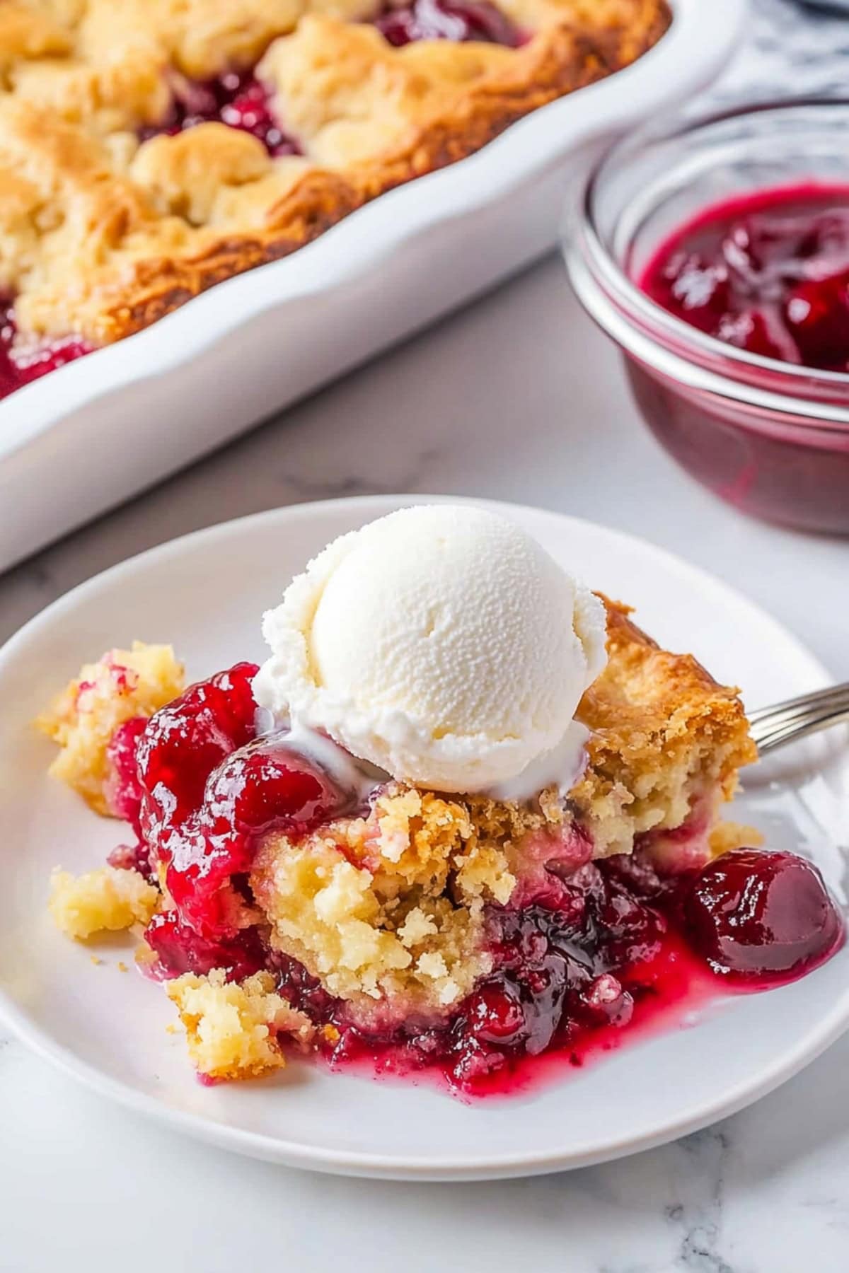 Cherry Pineapple Dump Cake served on a plate with a scoop of vanilla ice cream
