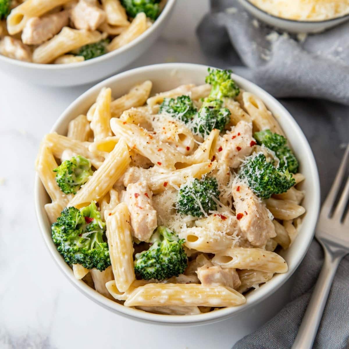 Homemade savory and flavorful chicken and broccoli pasta topped with grated parmesan cheese and red pepper flakes.