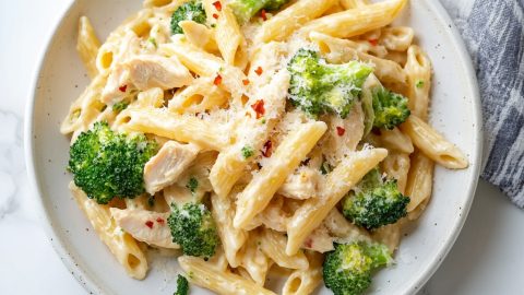 An overhead view of a plate of chicken and broccoli pasta.