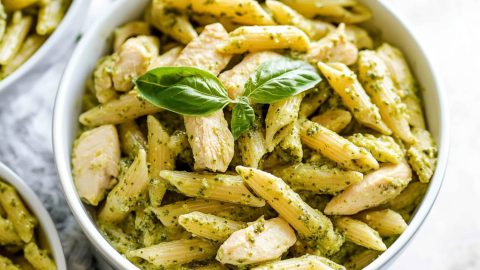 Creamy chicken pesto pasta in a bowl, topped with basil.