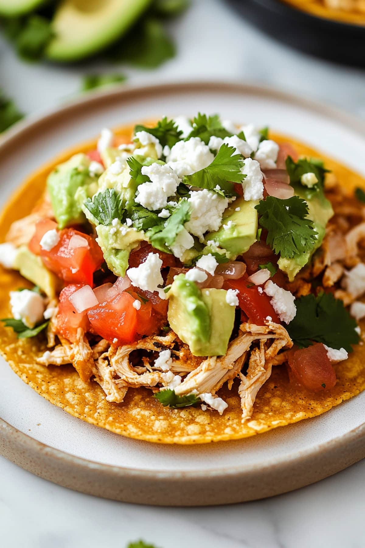 Chicken tostados with Chicken tostados made with crispy corn tortilla topped with refried beans, mashed avocado, shredded chicken, lettuce, tomato, red onion, cotija cheese and cilantro.
