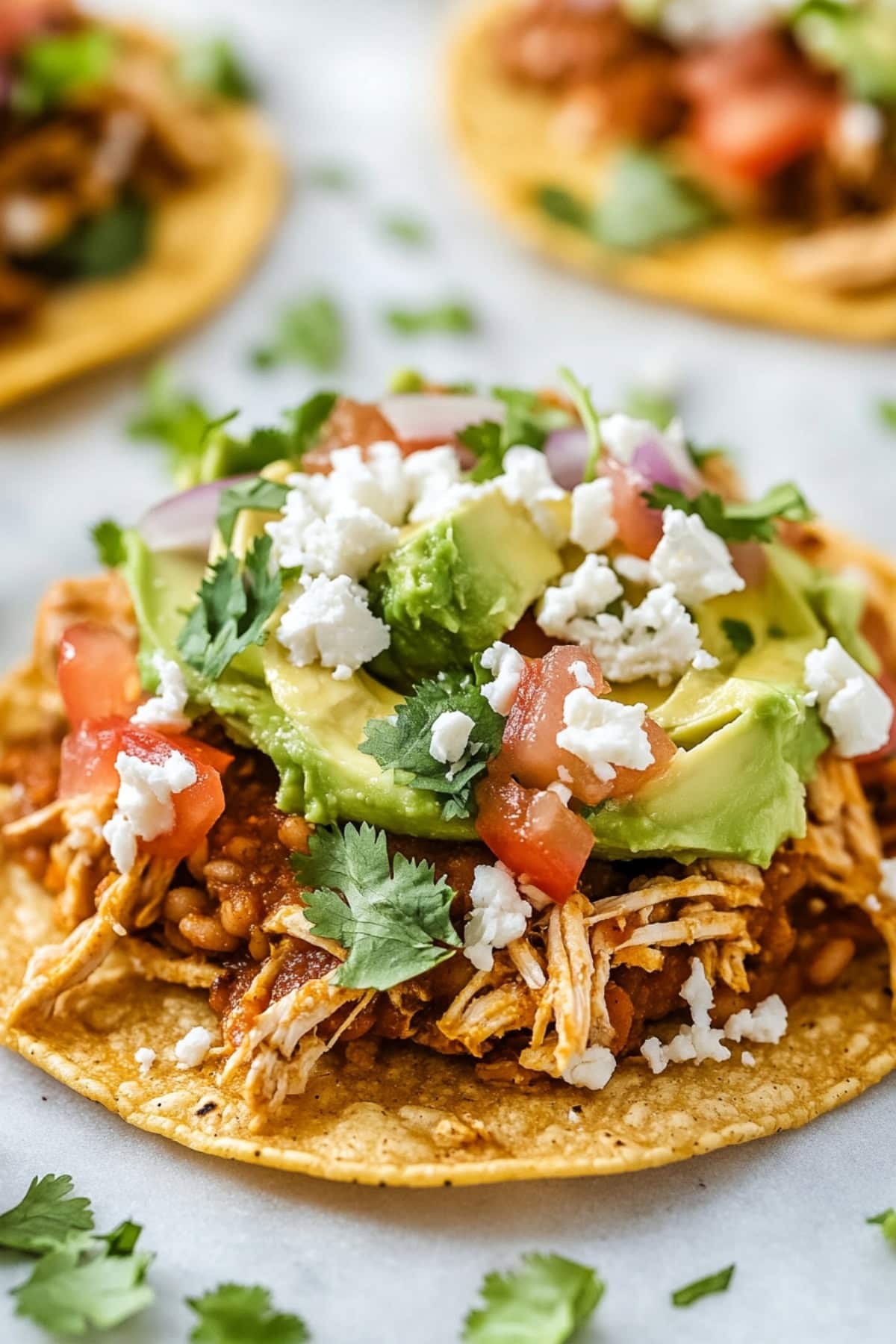 Chicken tostados made with crispy corn tortilla topped with refried beans, mashed avocado, shredded chicken, lettuce, tomato, red onion, cotija cheese and cilantro.
