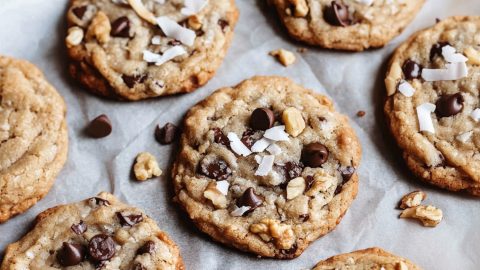 An overhead view of chocolate chip treasure cookies with nuts and coconut on parchment paper.