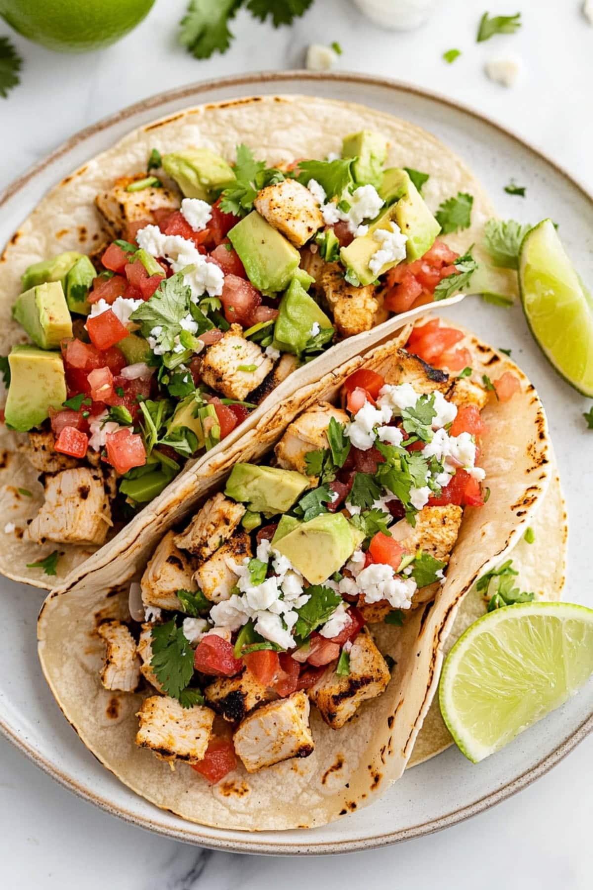 Cilantro lime chicken tacos with avocado, Mexican cheese, and tomatoes.