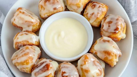 Cinnamon roll bites in a plate with vanilla glaze in the middle.