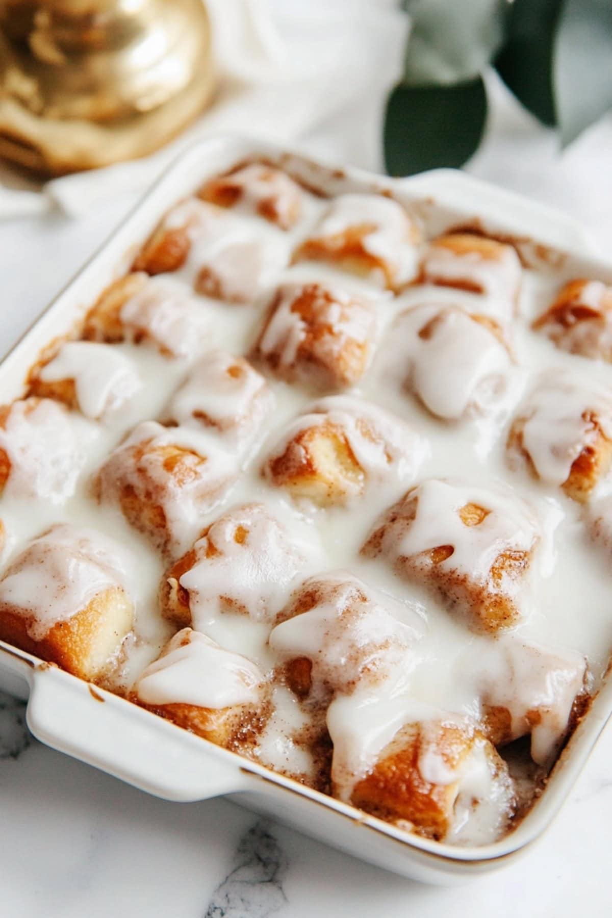 Biscuit bites in a baking dish covered in sweet vanilla glaze