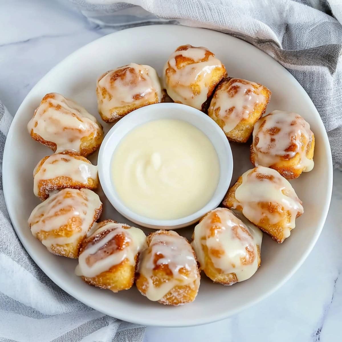 Cinnamon Roll Bites in a bowl with a small bowl of vanilla glaze in the middle. 