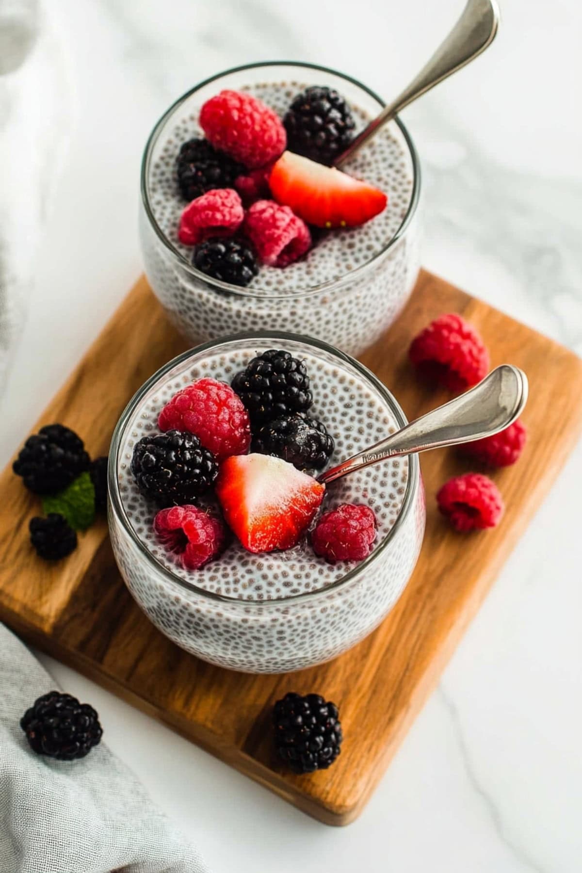 Healthy coconut chia pudding in glasses on a wooden board, top view.