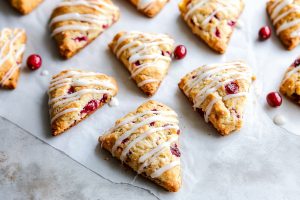 Delicious homemade cranberry scones drizzled with glaze on a parchment paper.