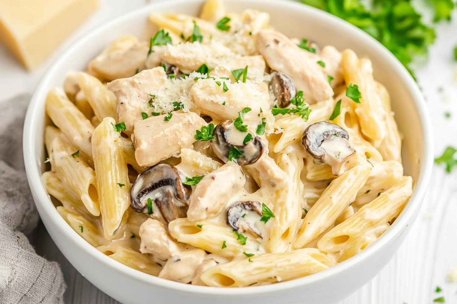 Serving of creamy chicken and mushroom pasta served in a white bowl.