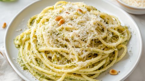 A plate of creamy lemon pesto pasta with grated parmesan cheese.