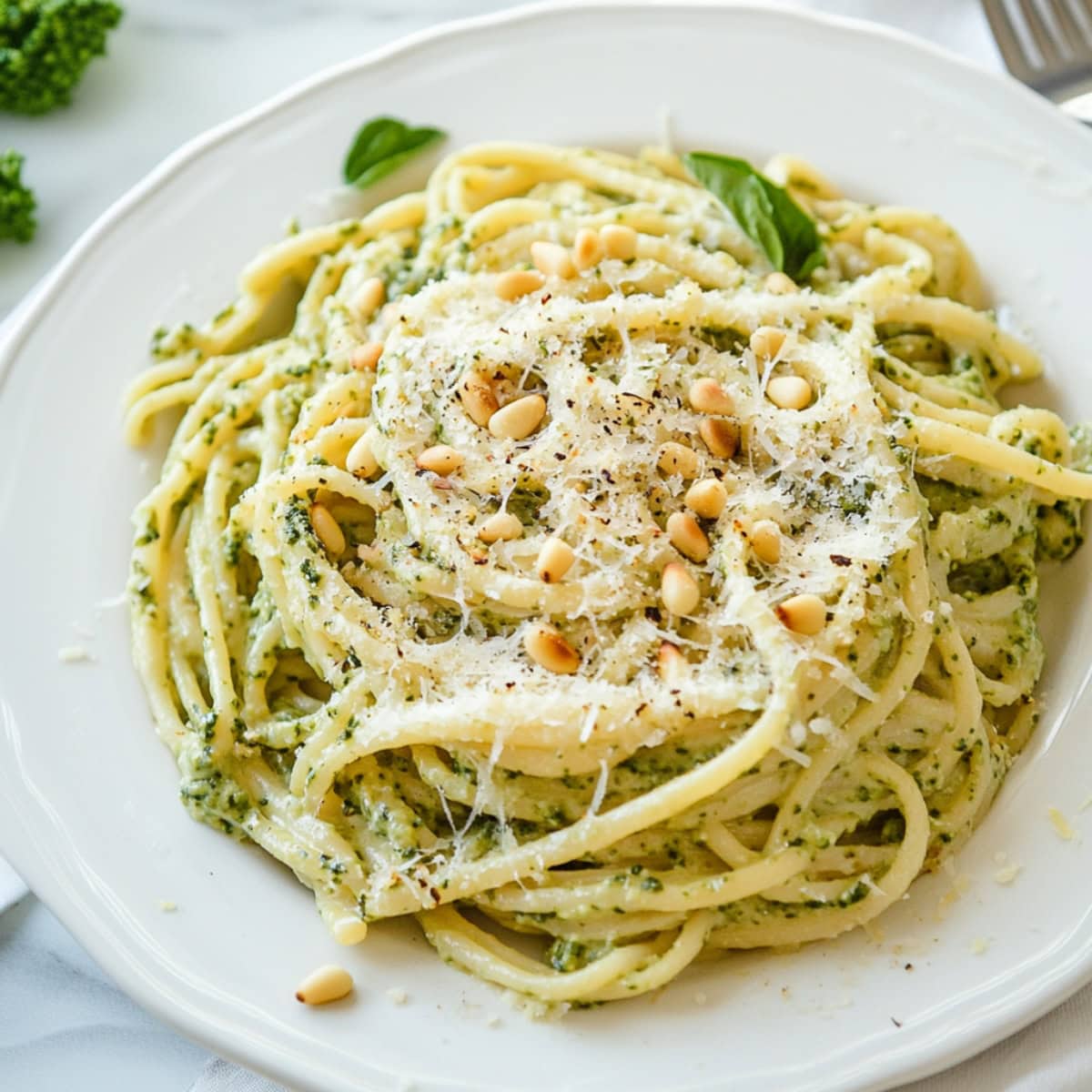 A close-up shot of creamy lemon pesto pasta, topped with freshly grated Parmesan and pine nuts