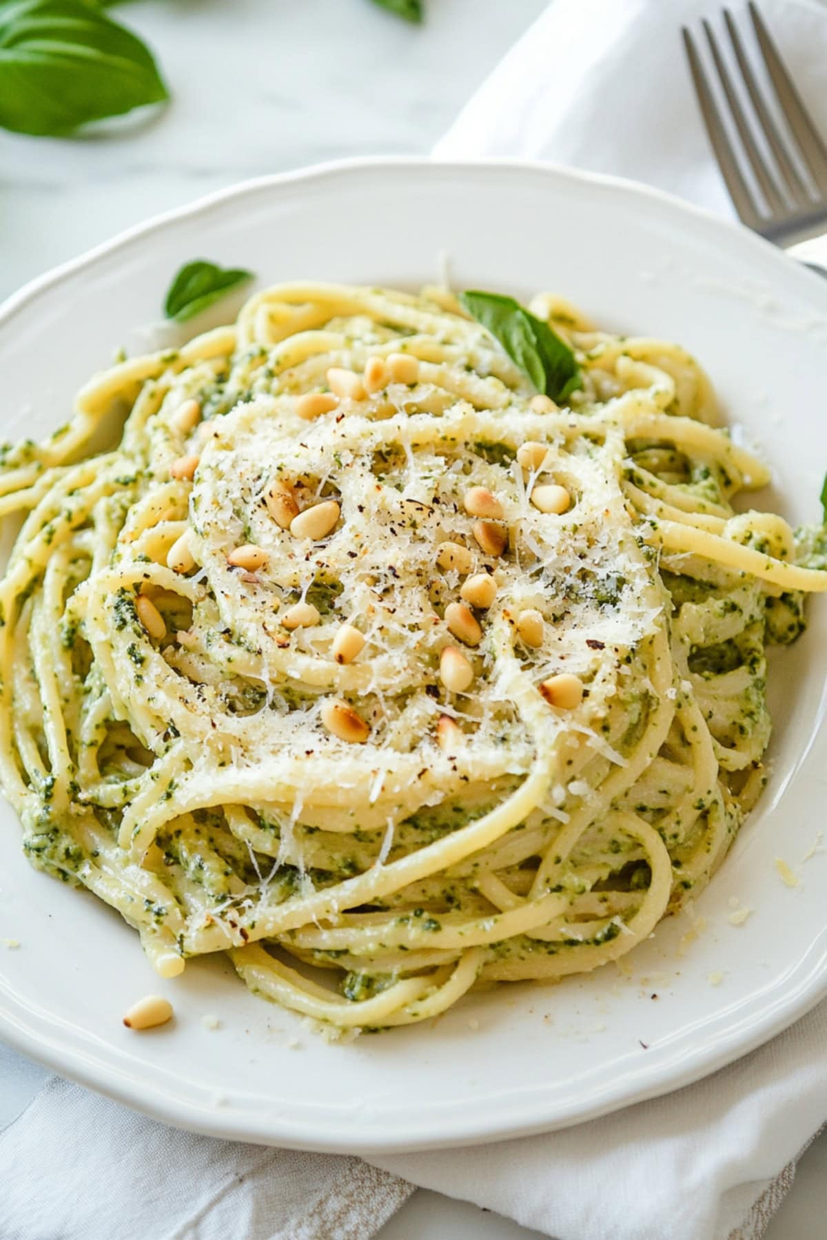 Homemade creamy lemon pesto pasta with toasted pine nuts and parmesan cheese on a plate, top view