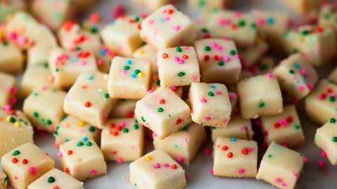 Bunch of square slices of shortbread bites scattered on a marble table.