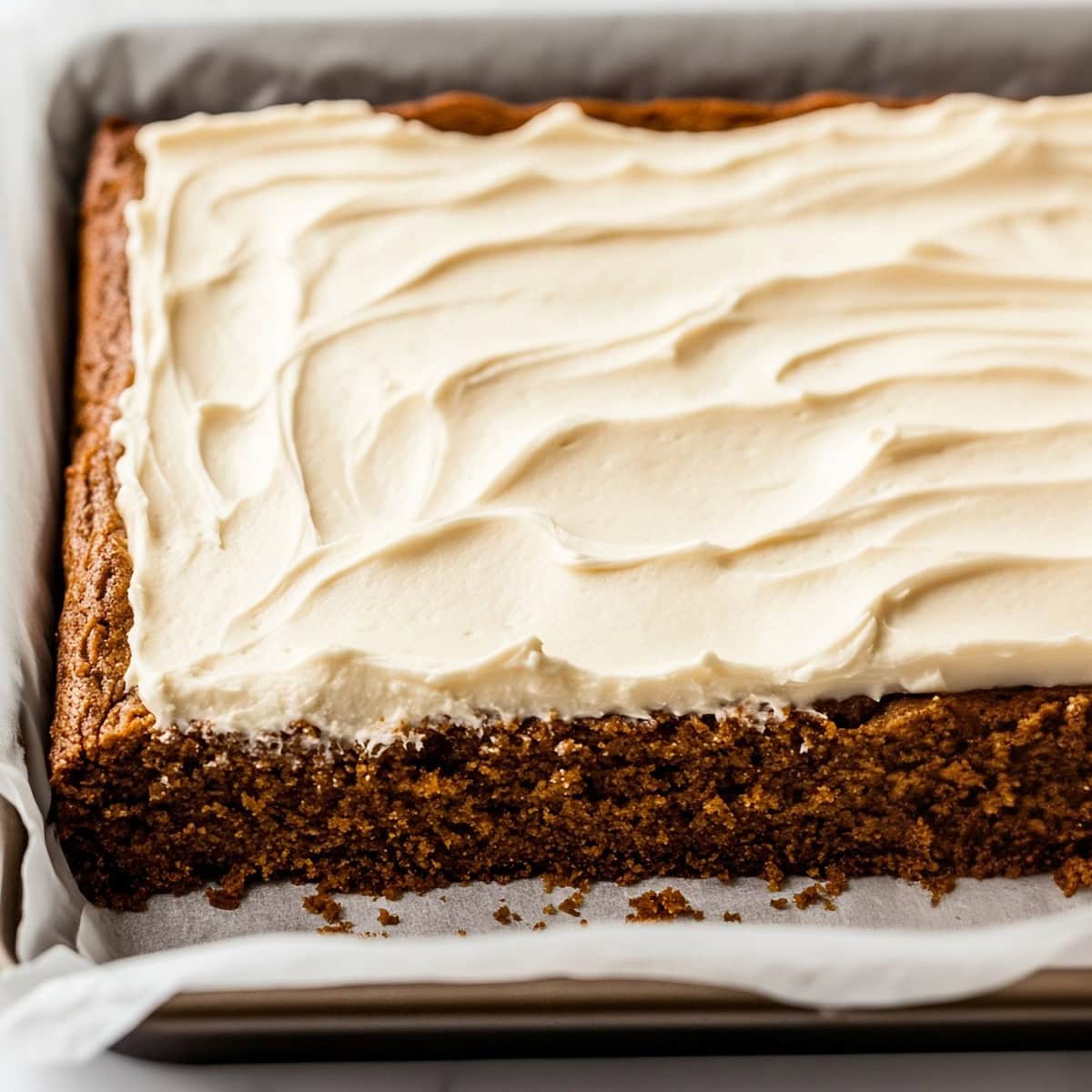 A freshly baked gingerbread sheet cake, with swirls of frosting spread evenly across the top.