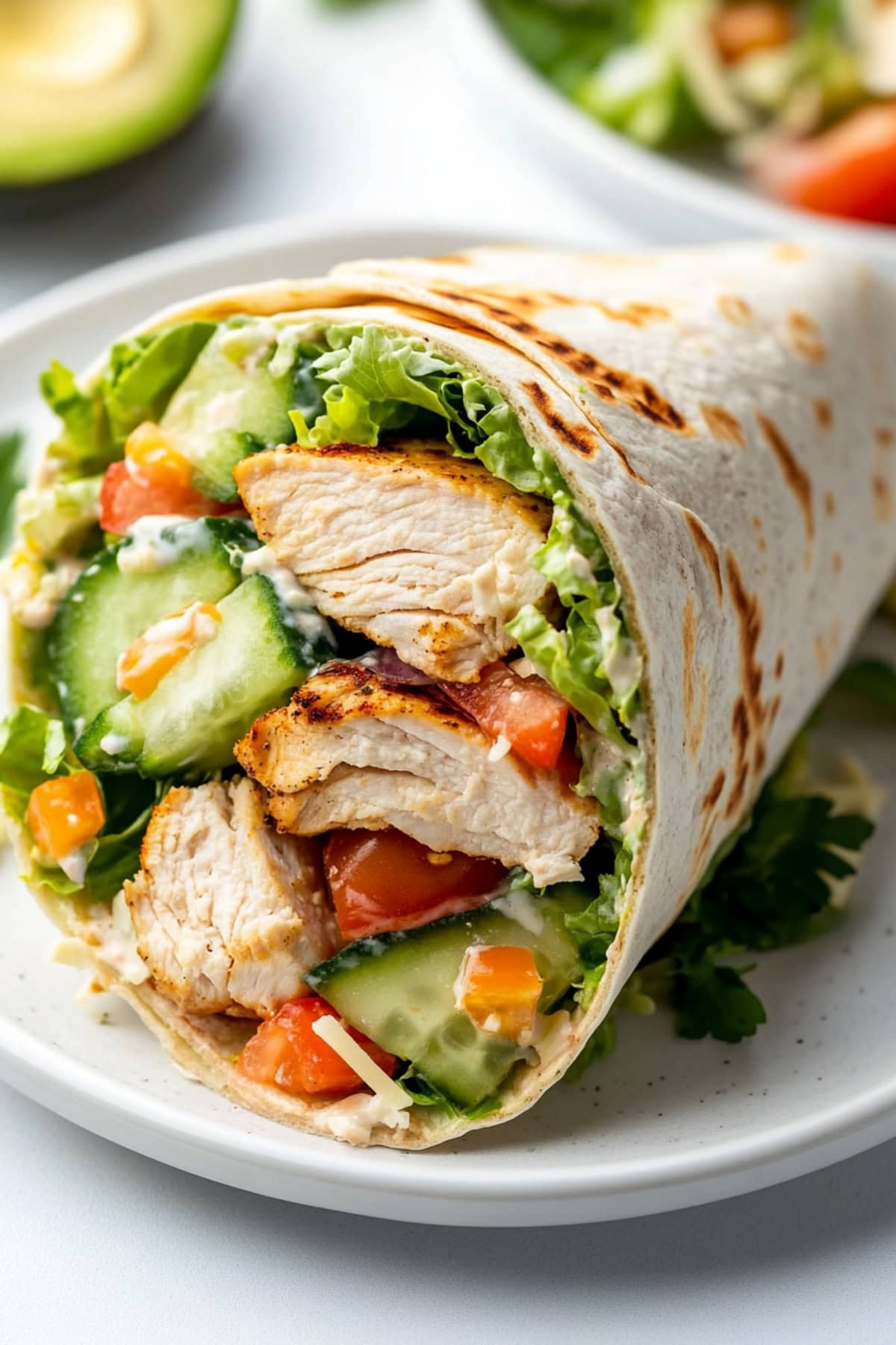 A plate of single grilled chicken wrap with veggies in a plate.