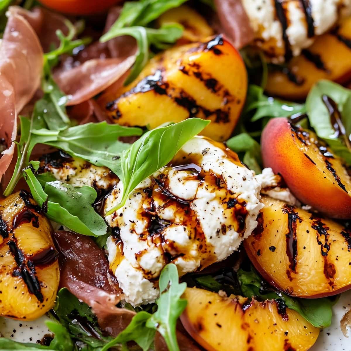 A close-up of juicy grilled peaches paired with creamy burrata, resting on a bed of arugula.