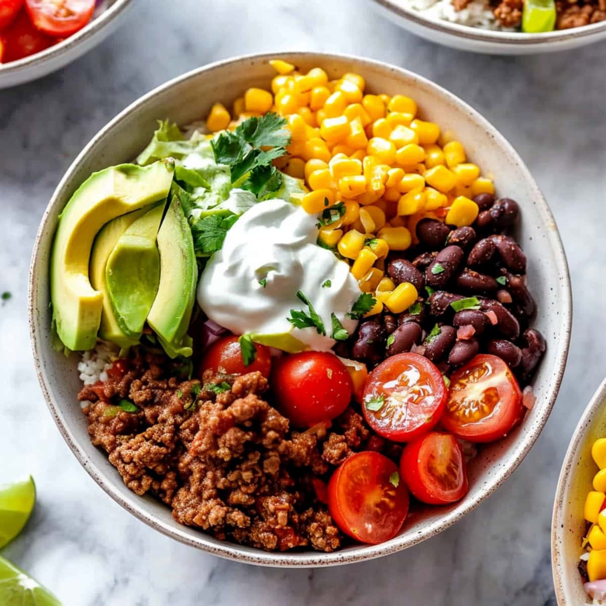 Burrito bowl made with ground beef, cilantro lime rice, black beans, corn and avocado.