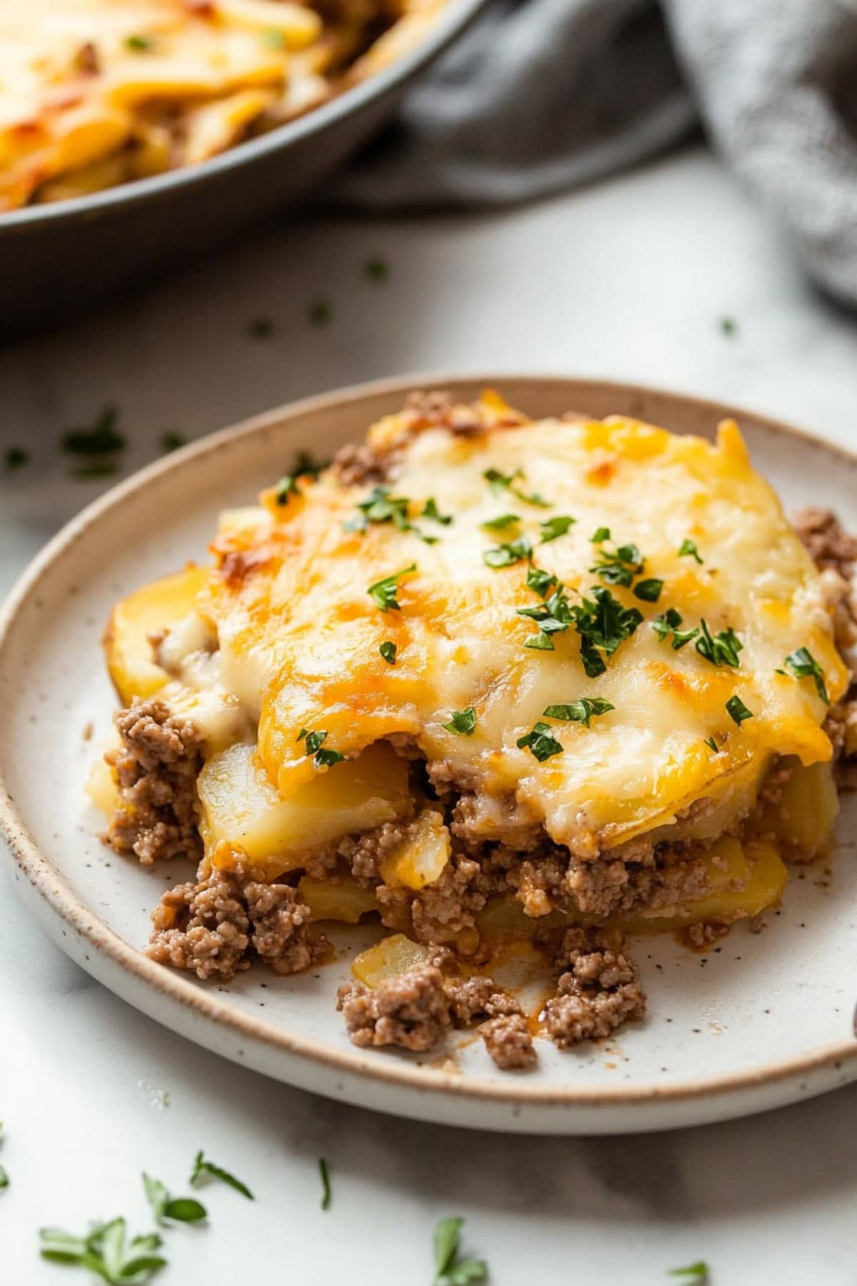 Hamburger potato casserole with cheese, garnished with herbs.