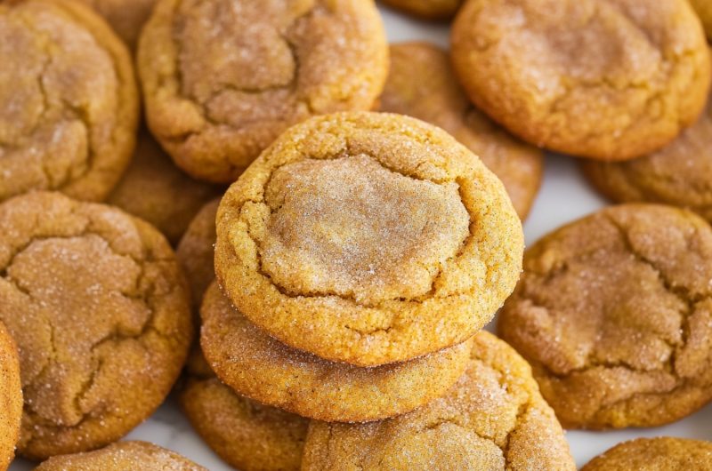 A festive autumn display of pumpkin snickerdoodle cookies on a white marble table.