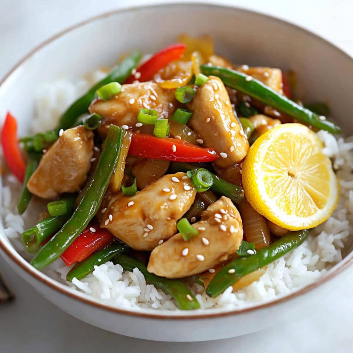 Lemon chicken stir-fry with vegetables, served with rice.