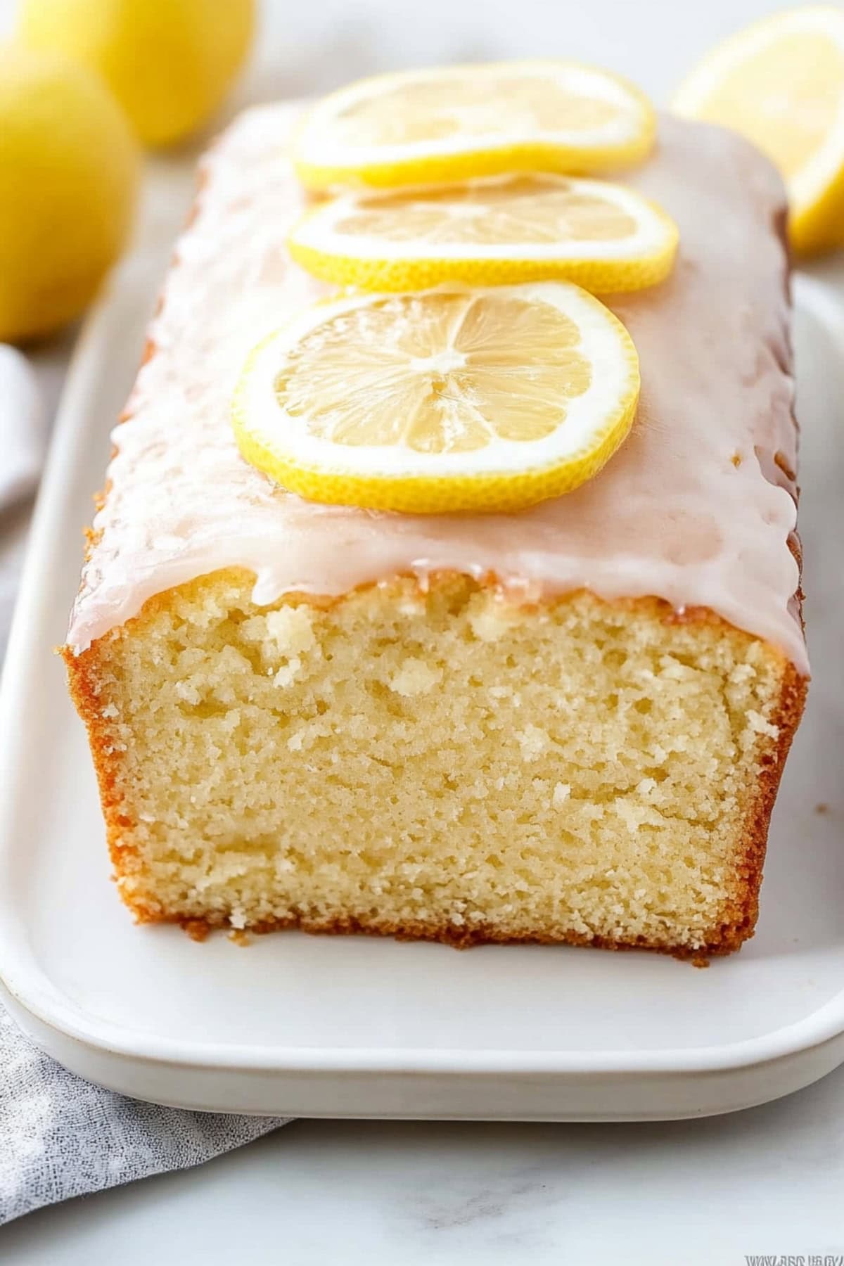 Lemon yogurt cake with glaze on a white platter, close up