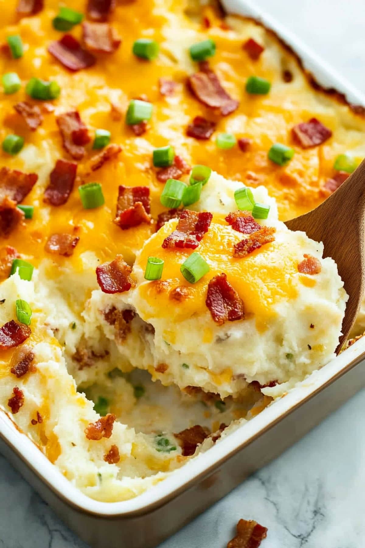 Loaded baked potato casserole fresh from the oven, with a golden cheese and crispy bacon pieces on top.