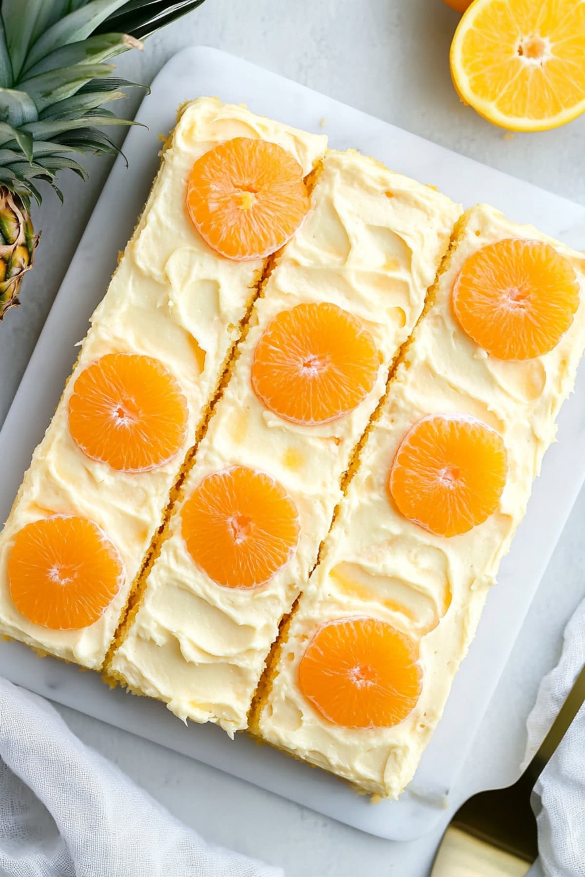 Mandarin orange cake with fresh orange and pineapple on the side, top view.