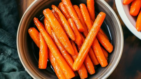 A serving of roasted maple glazed carrots in a bowl, overhead view.