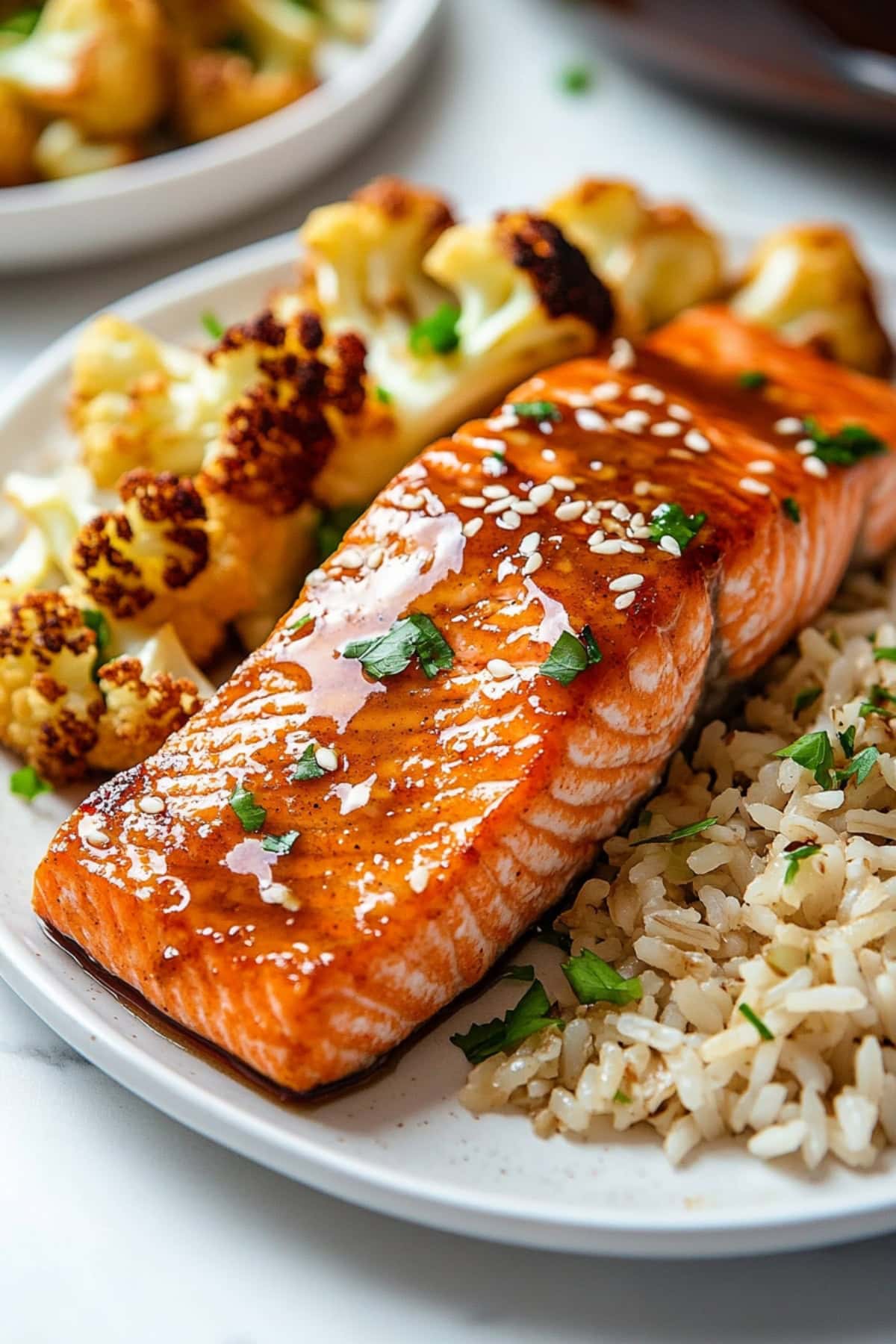 Maple glazed salmon garnished with chopped green onions served with rice and cauliflower.