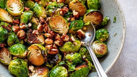 Golden brown maple roasted Brussels sprouts with nuts in a bowl, ready to be served.