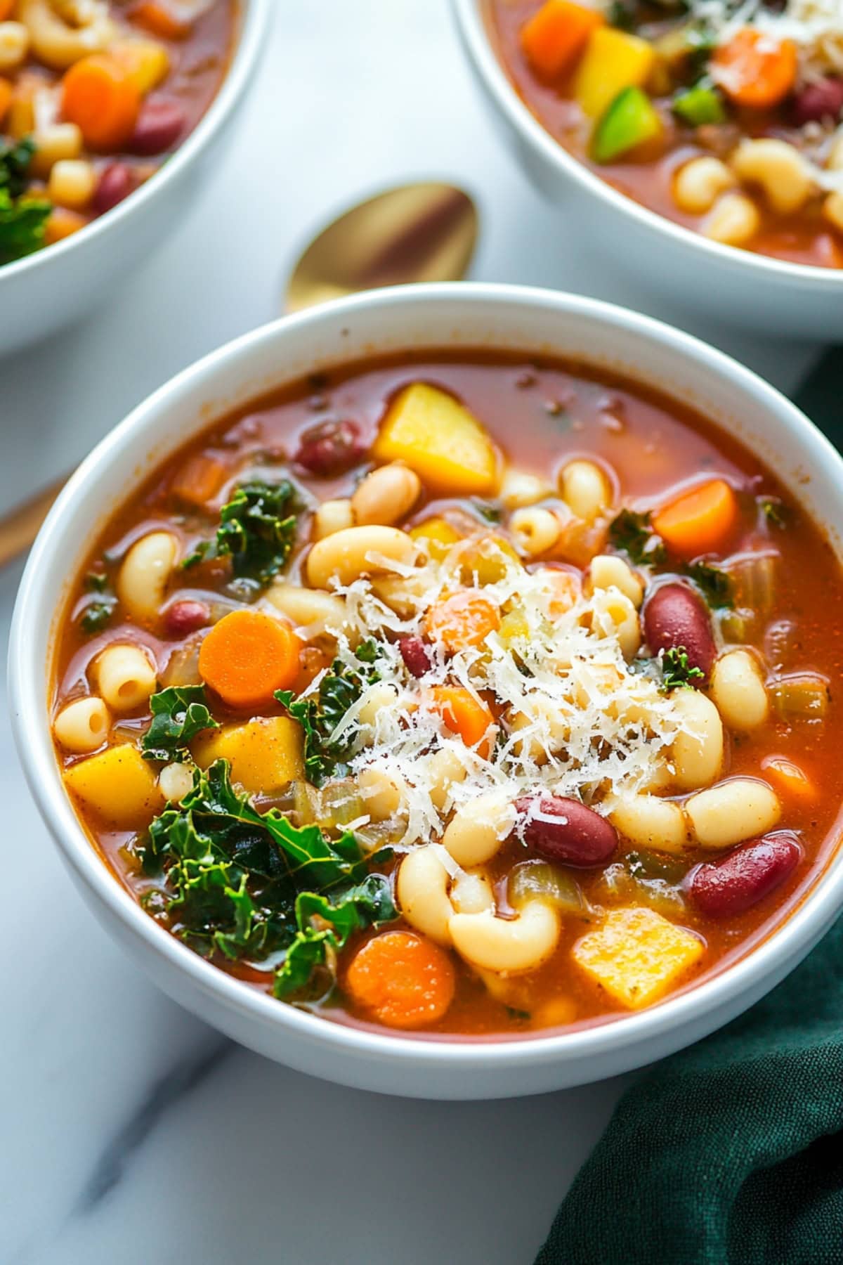 Minestrone soup garnished with shredded cheese served in a white bowl.