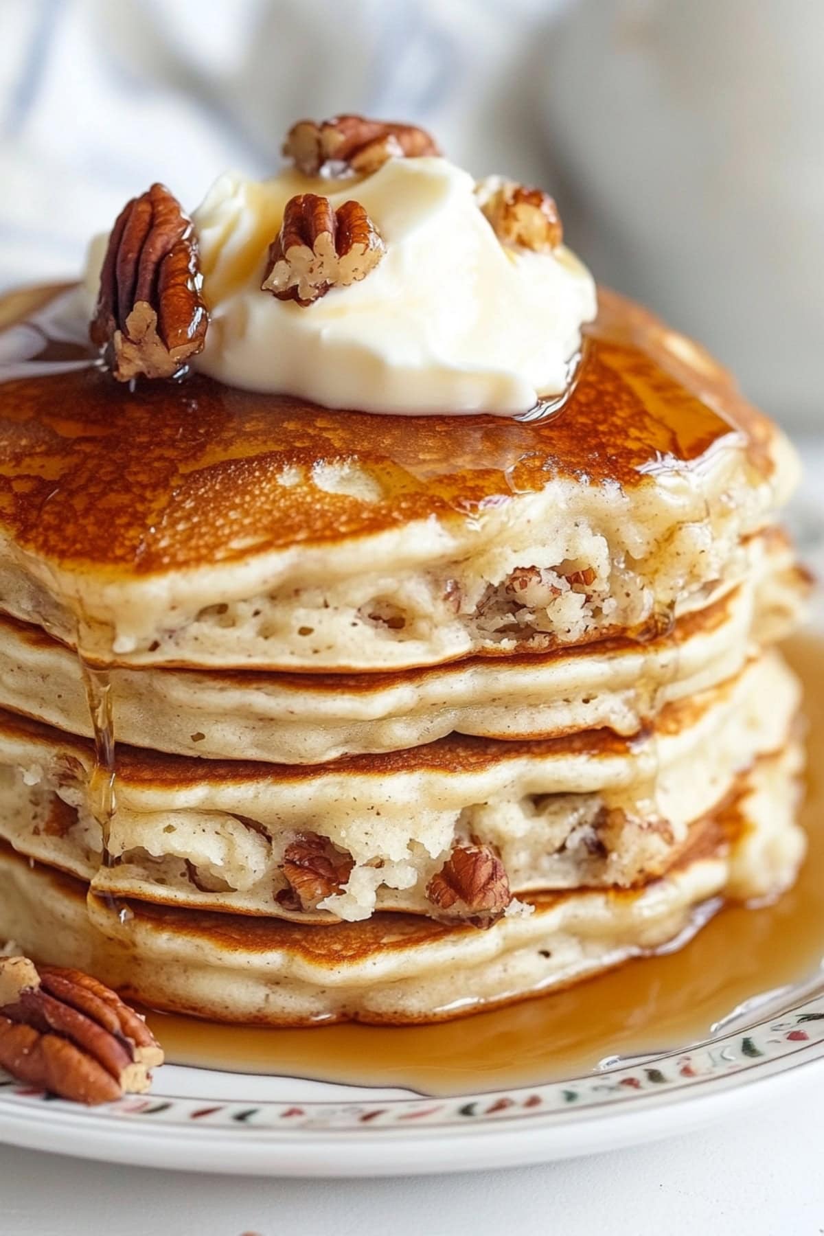 Warm pecan pancakes with syrup cascading down the sides.