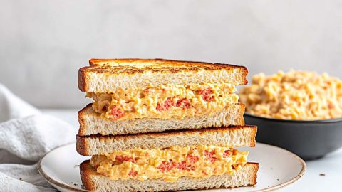 Pimento cheese sandwiches sliced in half served on a white plate.