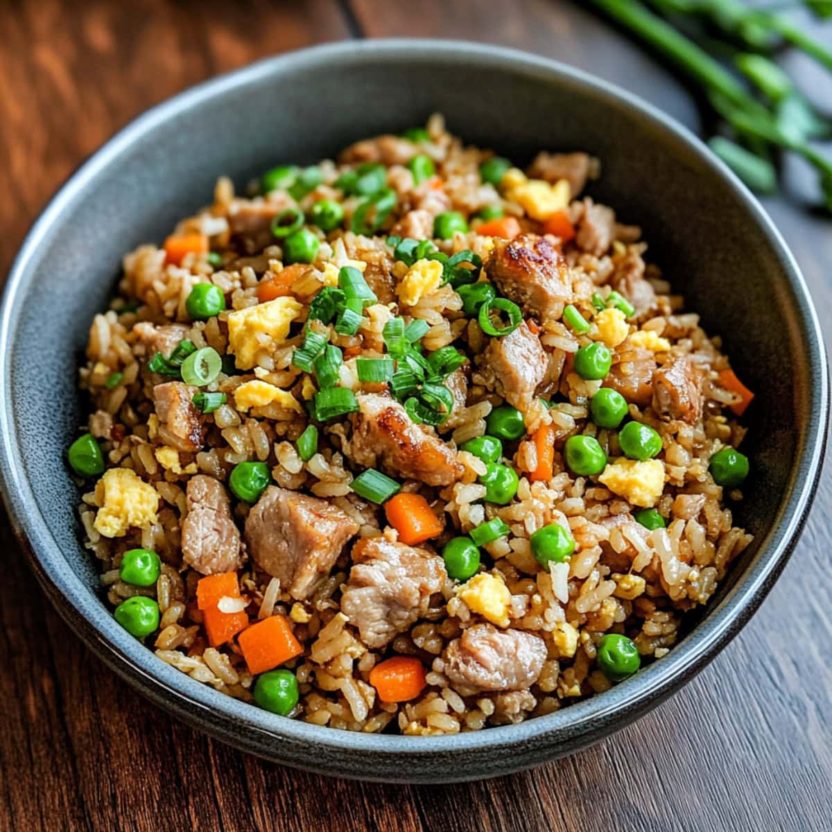 Savory pork fried rice in a bowl on a wooden board.