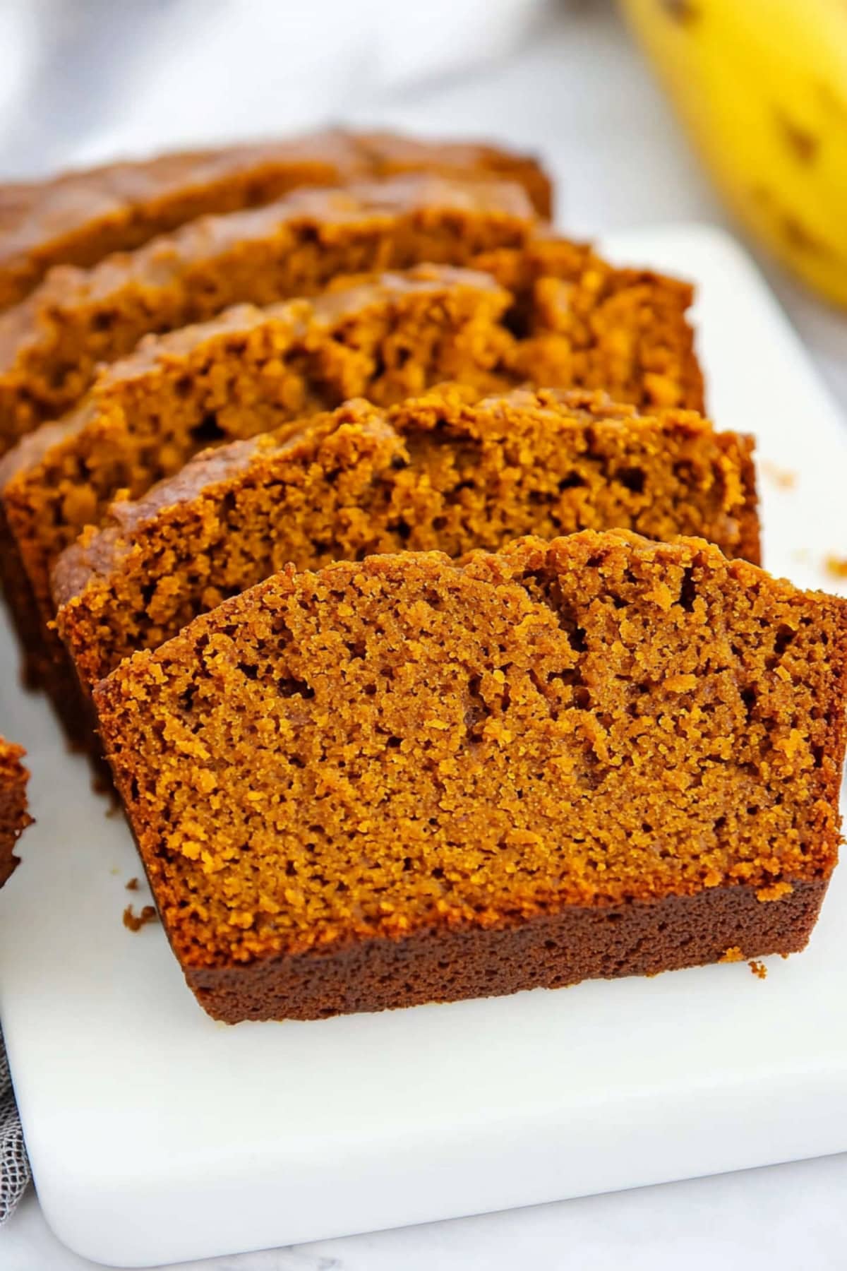 A thick slice of spiced pumpkin banana bread, with a moist texture and a golden crust.