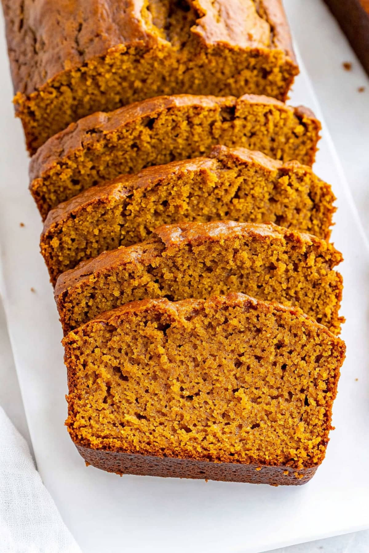 Homemade sliced pumpkin banana bread in a white platter.