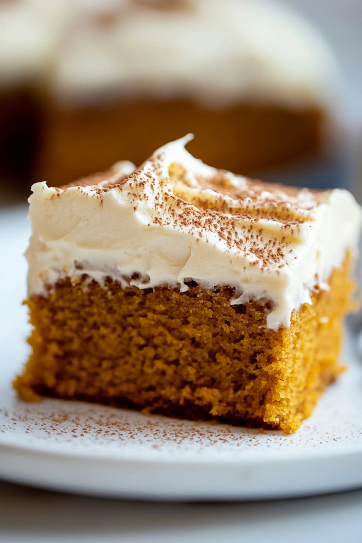 A slice of pumpkin cake served on a white plate, showing its rich orange texture.