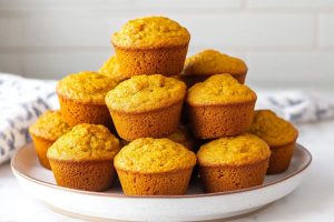 Pumpkin cornbread muffins with a golden hue, served in a white plate.