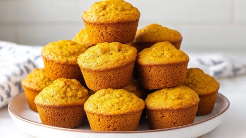 Pumpkin cornbread muffins with a golden hue, served in a white plate.