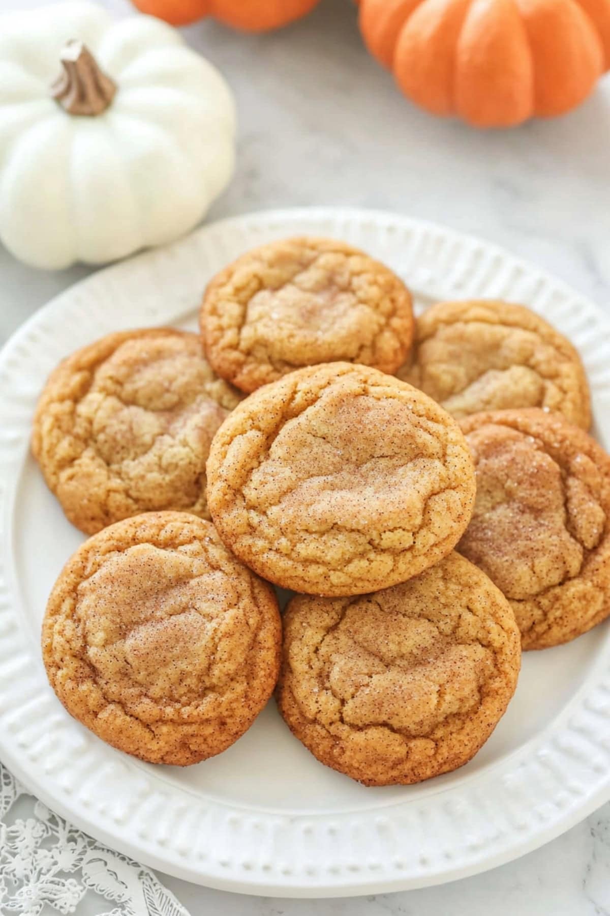 Pumpkin snickerdoodle cookies on a plate with pumpkins on the side, top view