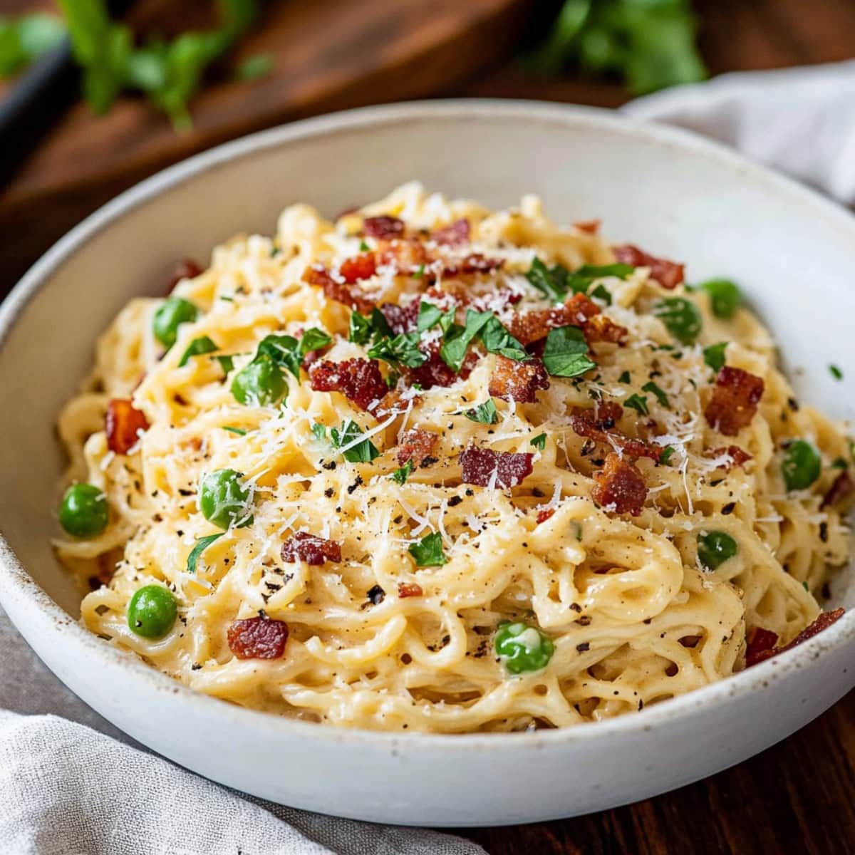 A serving of ramen carbonara with green peas, crumbled bacon, parmesan cheese and chopped parsley. 