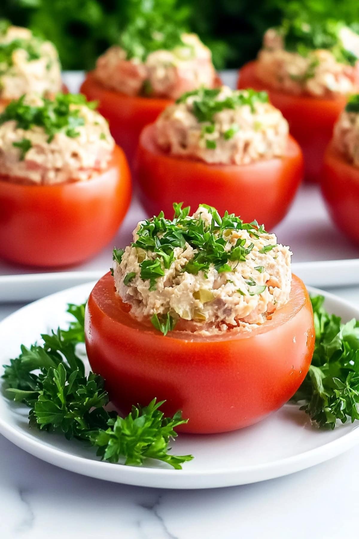 Tuna stuffed large red tomato served in a white plate.