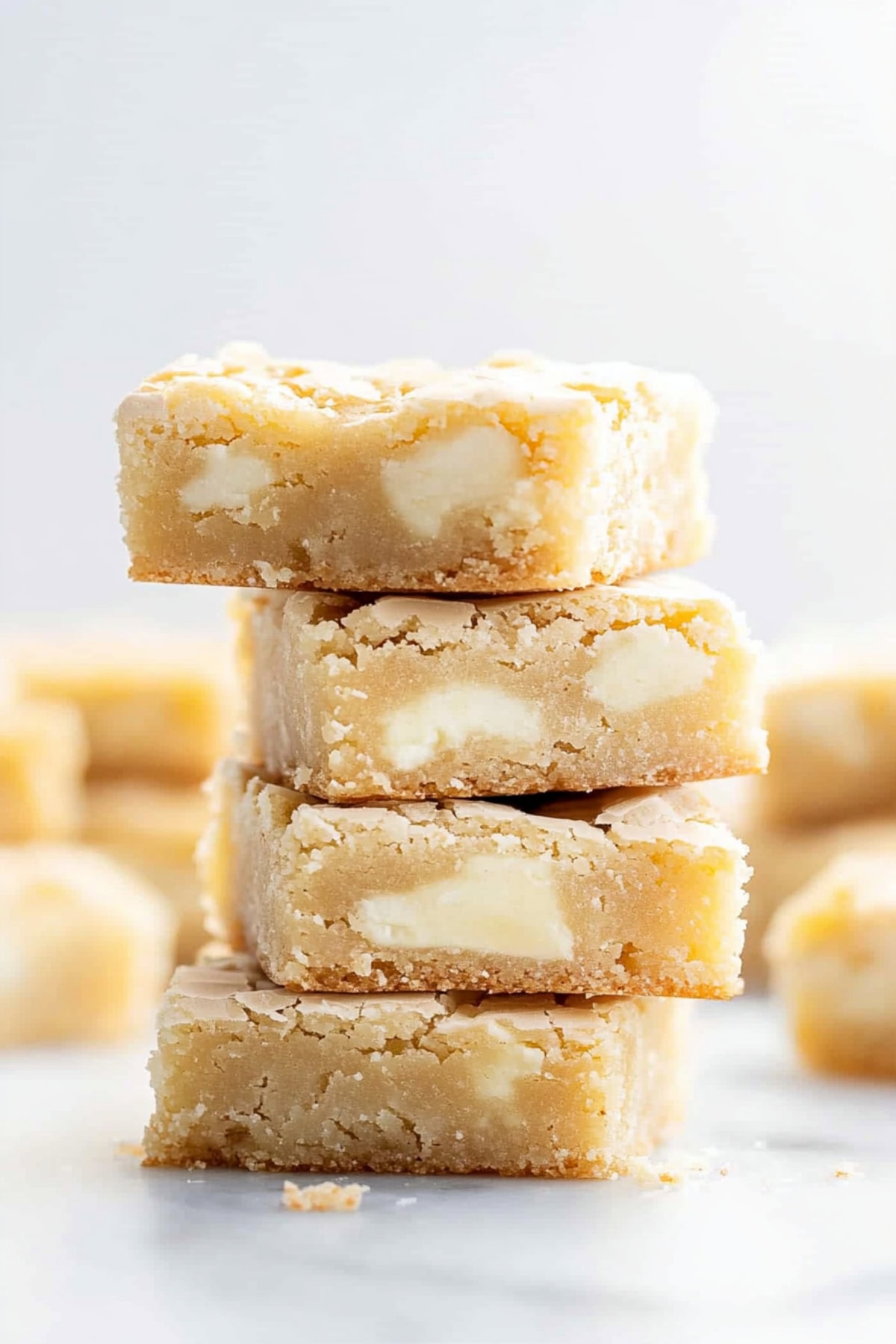 Chewy white chocolate brownies stacked on a light table, side view