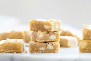 Bunch of white chocolate brownies bars lying on a marble surface.