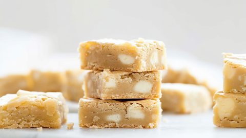 Bunch of white chocolate brownies bars lying on a marble surface.