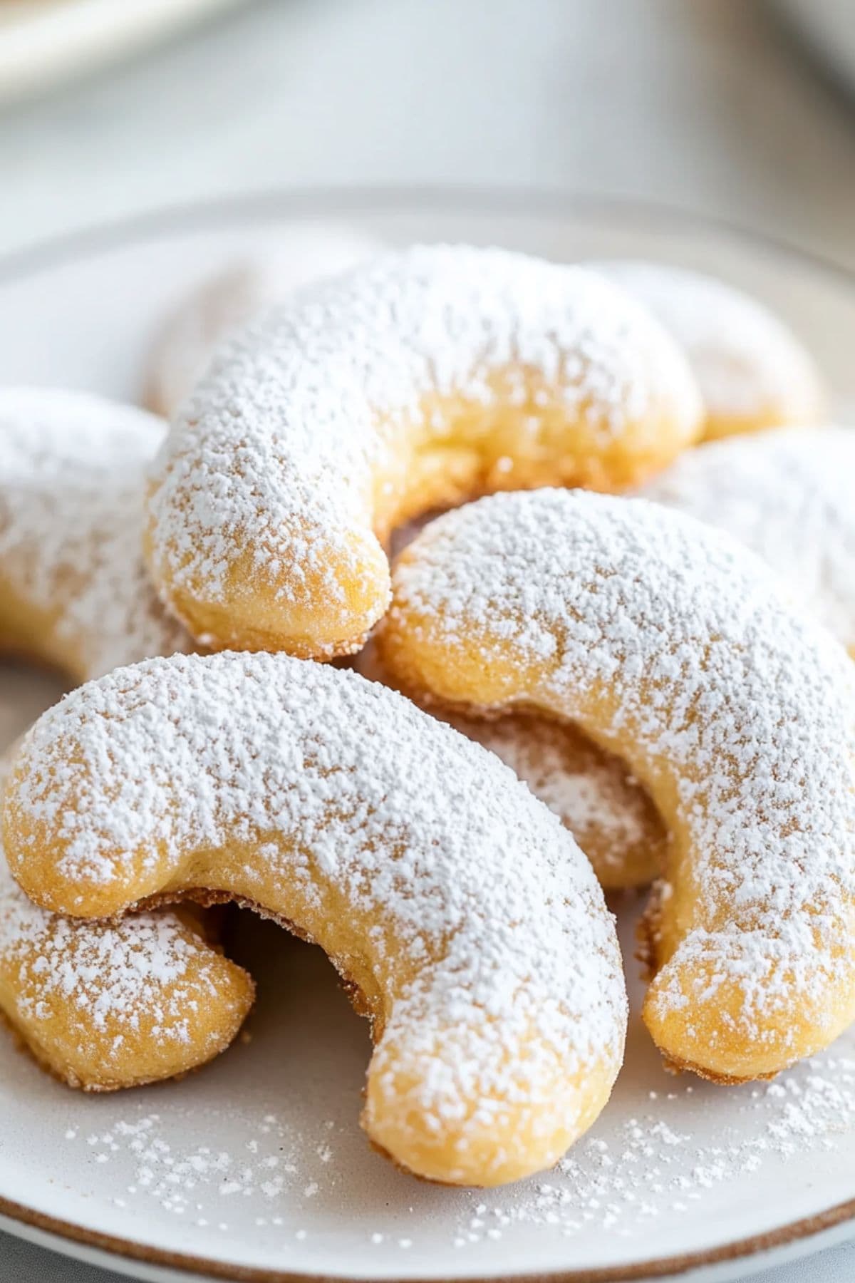 A plate of powdered sugar coated crescent cookies, close up