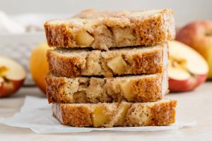 Stacked homemade apple cinnamon bread sitting on a parchment paper.