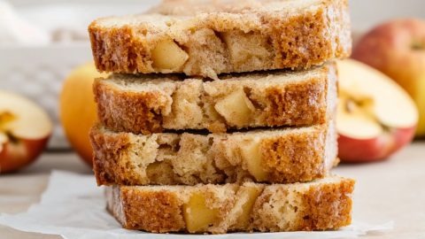 Stacked homemade apple cinnamon bread sitting on a parchment paper.